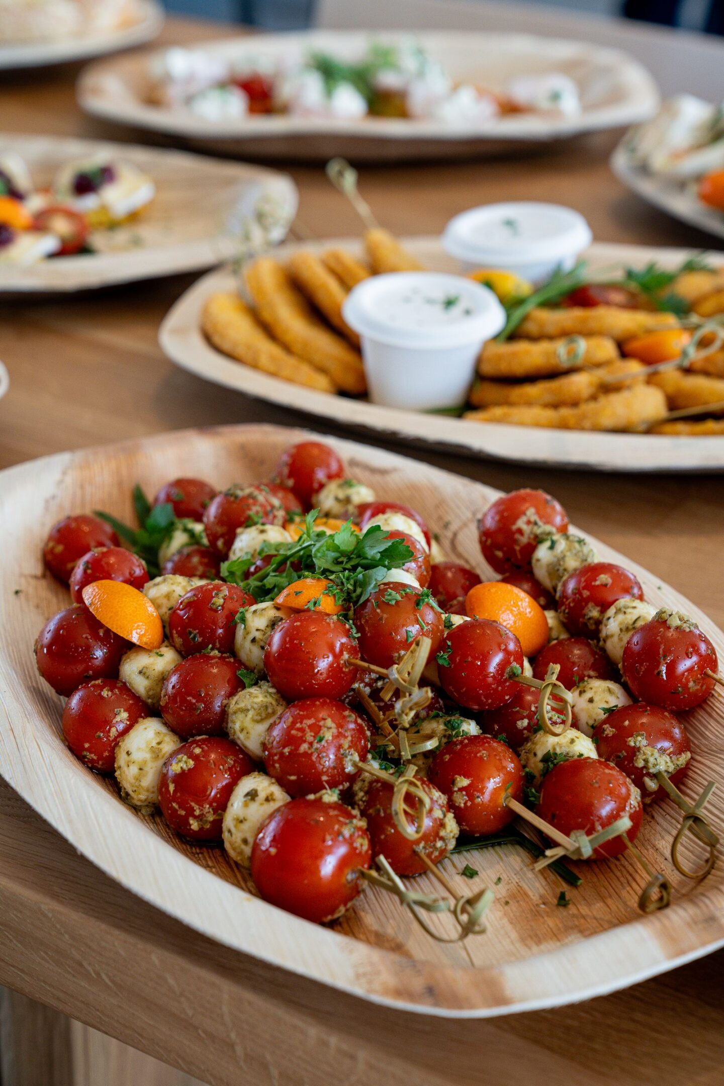 Plank met spiesjes van cherrytomaat, mozzarella en groene blaadjes als koud hapje voor een feestje